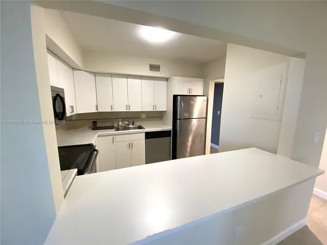 a kitchen with a refrigerator a stove top oven a refrigerator and white cabinets