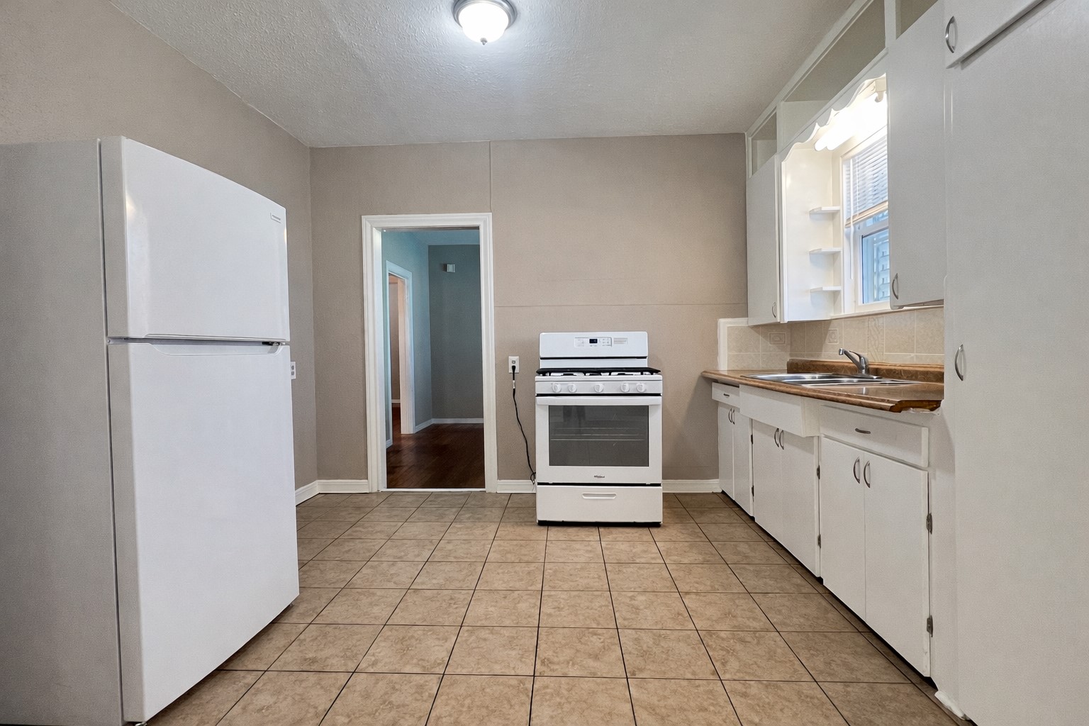 4917 Avenue R 1/2 Galveston, TX 77551 - Photo 3 of 21 Galveston TX kitchen with tile flooring, white appliances, and natural light from nearby coastal windows.