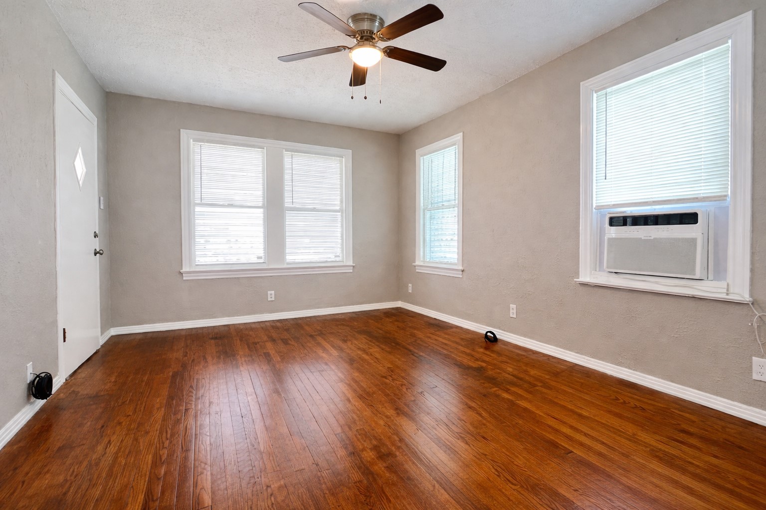 4917 Avenue R 1/2 Galveston, TX 77551 - Photo 6 of 21 Hardwood floor living area with ceiling fan and double windows in a Galveston Island home.