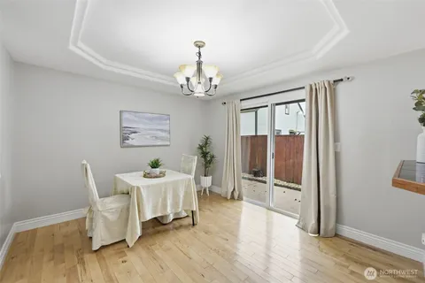 a dining room with wooden floor a chandelier a glass table and chairs