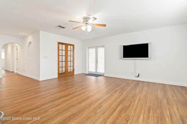 a view of an empty room with wooden floor and a window