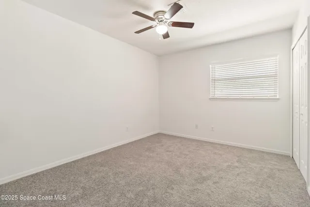an empty room with a window and a fan