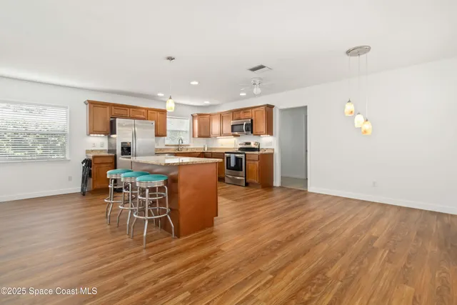 a living room with stainless steel appliances furniture a dining table and a window