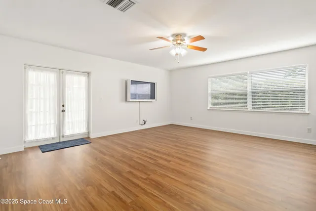 a view of an empty room with a window and wooden floor