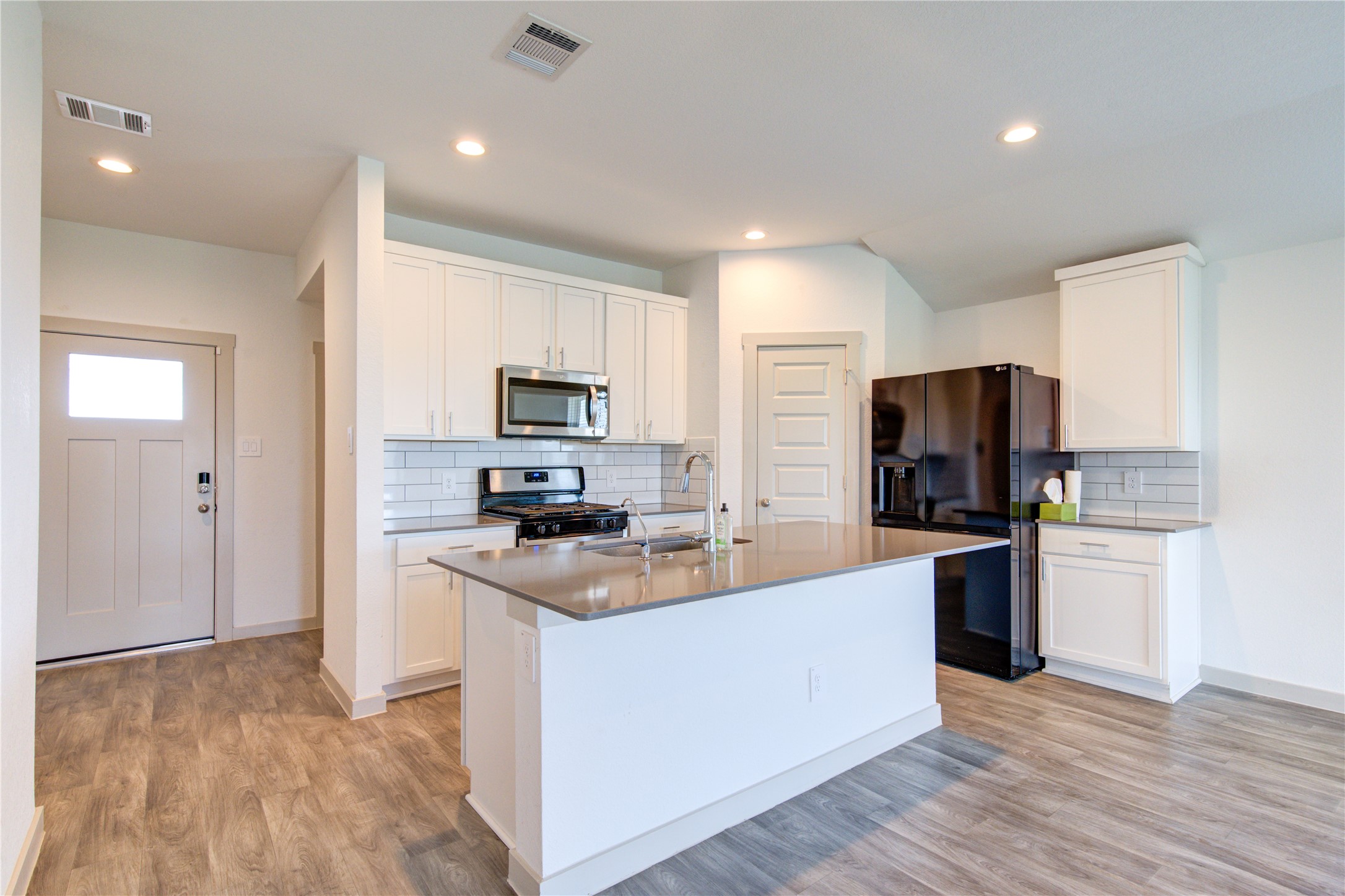 41 Desert Spring Lane Manvel, TX 77578 - Photo 11 of 33 a kitchen with stainless steel appliances a stove top oven a sink a refrigerator white cabinets and wooden floor