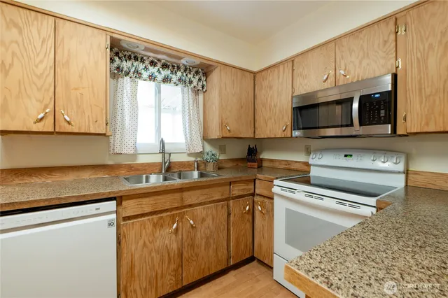 a kitchen with stainless steel appliances granite countertop a sink a stove a microwave and cabinets