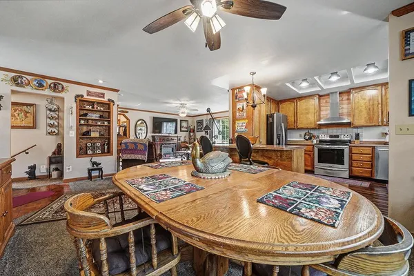 a kitchen with stainless steel appliances granite countertop a stove a sink a dining table and chairs with wooden floor