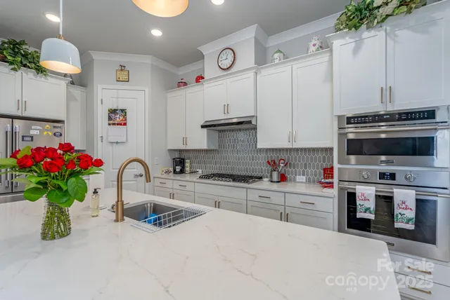 a kitchen with kitchen island granite countertop a sink and white cabinets