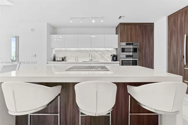 a kitchen with kitchen island a dining table chairs and a refrigerator