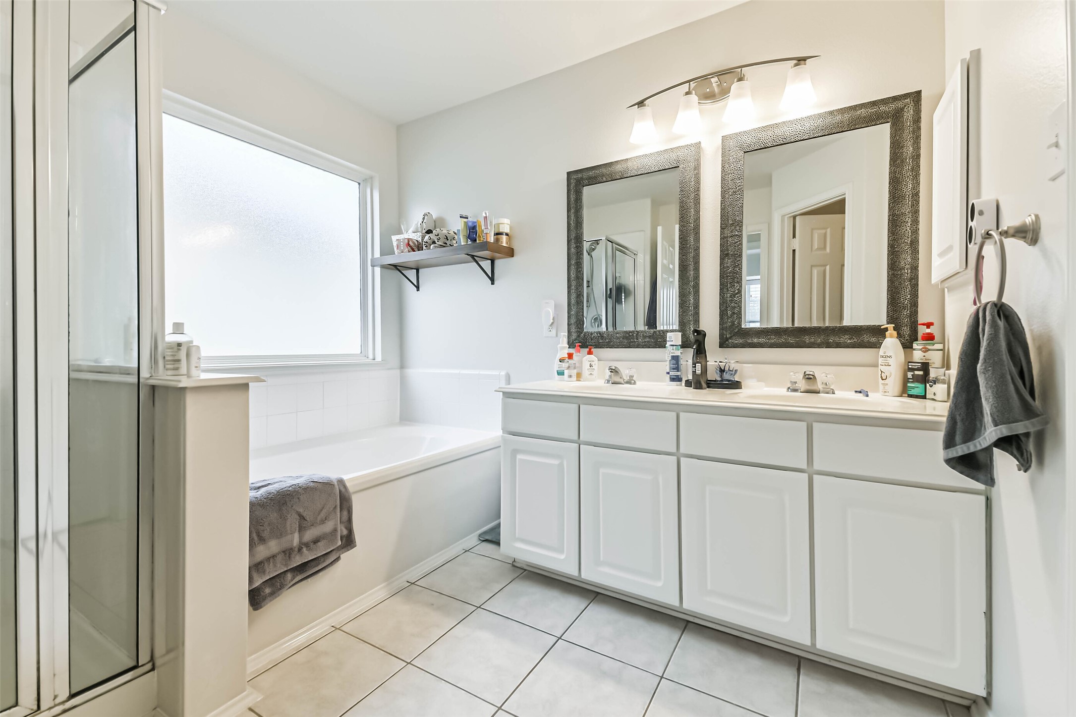 22538 Goss Spring Court Spring, TX 77373 - Photo 25 of 36 This bathroom features a modern design with a spacious layout, including a glass-enclosed shower and a large soaking tub. It has a double vanity with ample storage, elegant mirrors, and bright lighting. The neutral color palette enhances the clean, fresh ambiance.