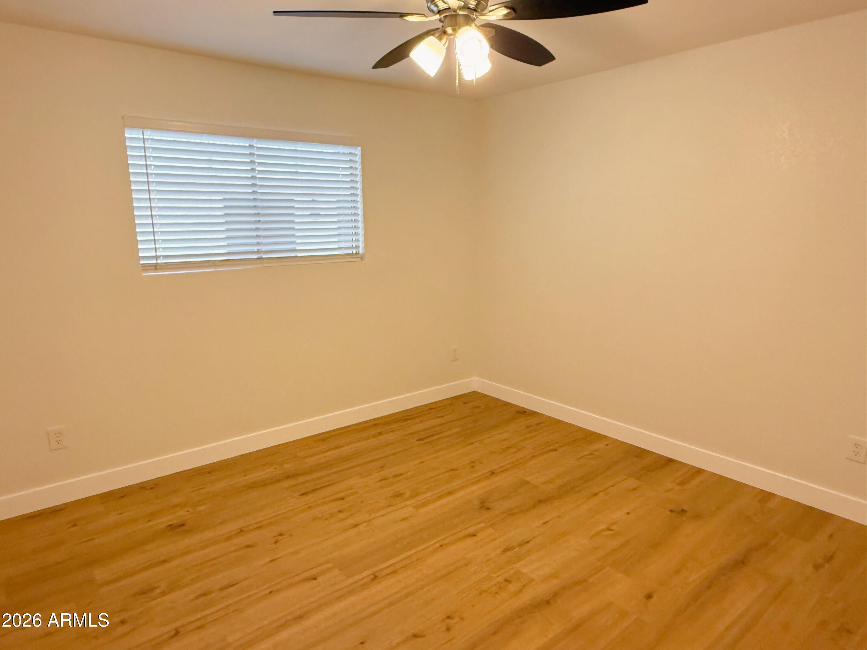 18202 North Cave Creek Road, Unit 148 Phoenix, AZ 85032 - Photo 11 of 19 a view of an empty room with wooden floor and a window
