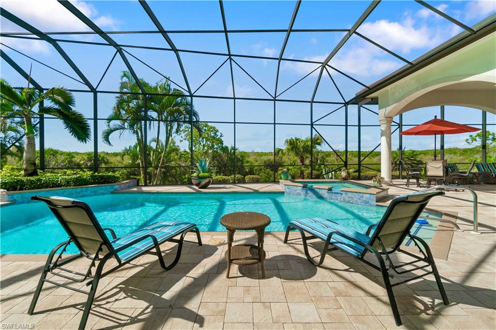 208 Audubon Boulevard Naples, FL 34110 - Photo 14 of 45 a view of a swimming pool with a table and chairs under an umbrella