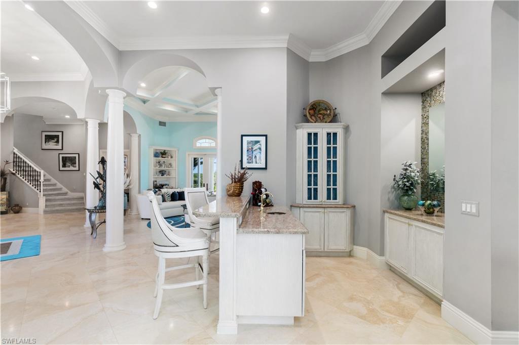 208 Audubon Boulevard Naples, FL 34110 - Photo 18 of 45 a dining hall with couches a flat tv screen and potted plant with kitchen view