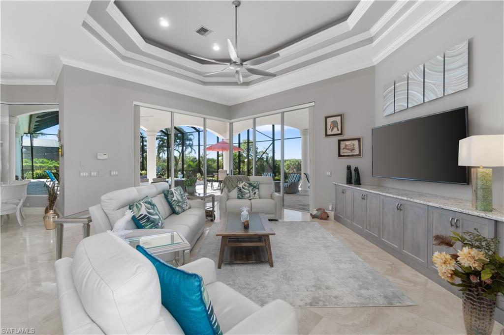 208 Audubon Boulevard Naples, FL 34110 - Photo 24 of 45 a living room with furniture a chandelier and a flat screen tv