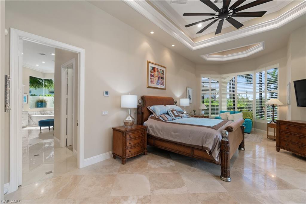 208 Audubon Boulevard Naples, FL 34110 - Photo 27 of 45 a bedroom with a bed and a chandelier