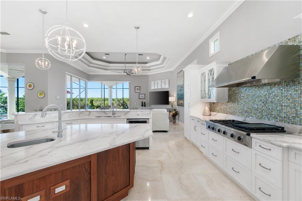 208 Audubon Boulevard Naples, FL 34110 - Photo 5 of 45 a large kitchen with a lot of stainless steel appliances wooden floor and a chandelier