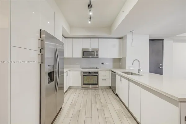 a kitchen with white cabinets stainless steel appliances and a sink