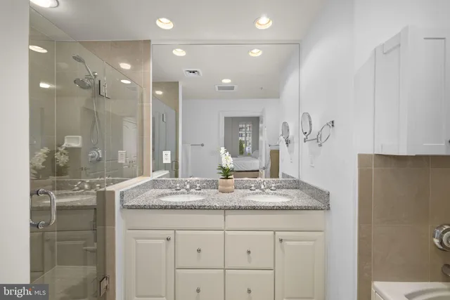 a bathroom with a granite countertop sink a mirror and a shower