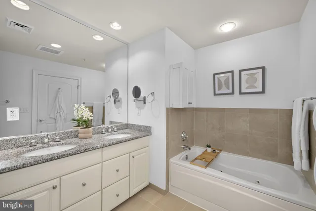 a bathroom with a granite countertop tub a sink and a shower