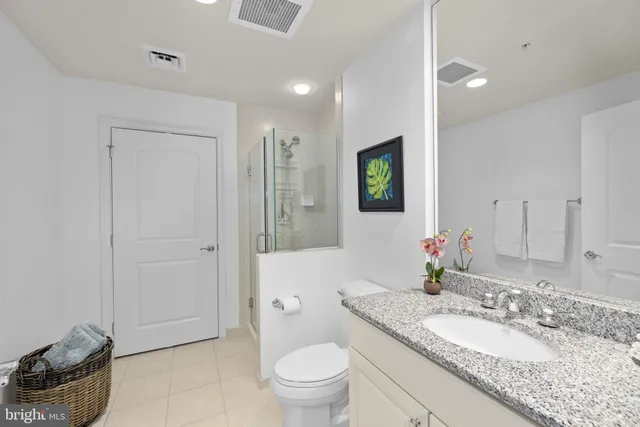 a bathroom with a granite countertop sink a toilet a mirror and shower