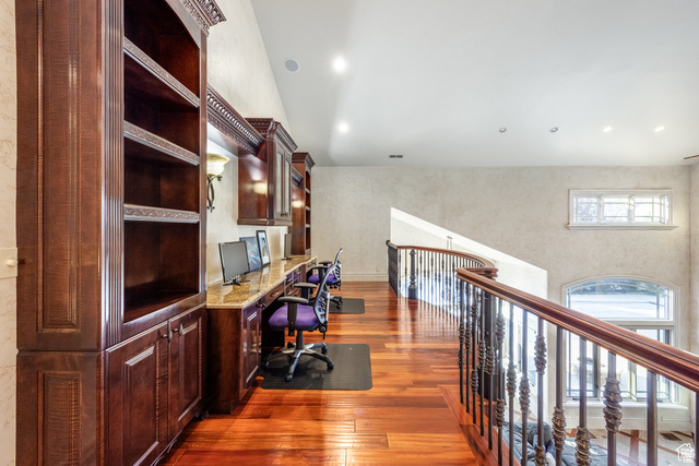 694 West Cephus Road Draper, UT 84020 - Photo 60 of 148 Upper-level hall featuring rich wood-finish flooring, built-in cabinetry and shelving, a workstation with stone-finish countertops, recessed lighting, and a curved staircase with ornate iron balusters