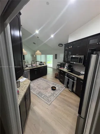 a kitchen with stainless steel appliances kitchen island granite countertop a refrigerator stove and sink