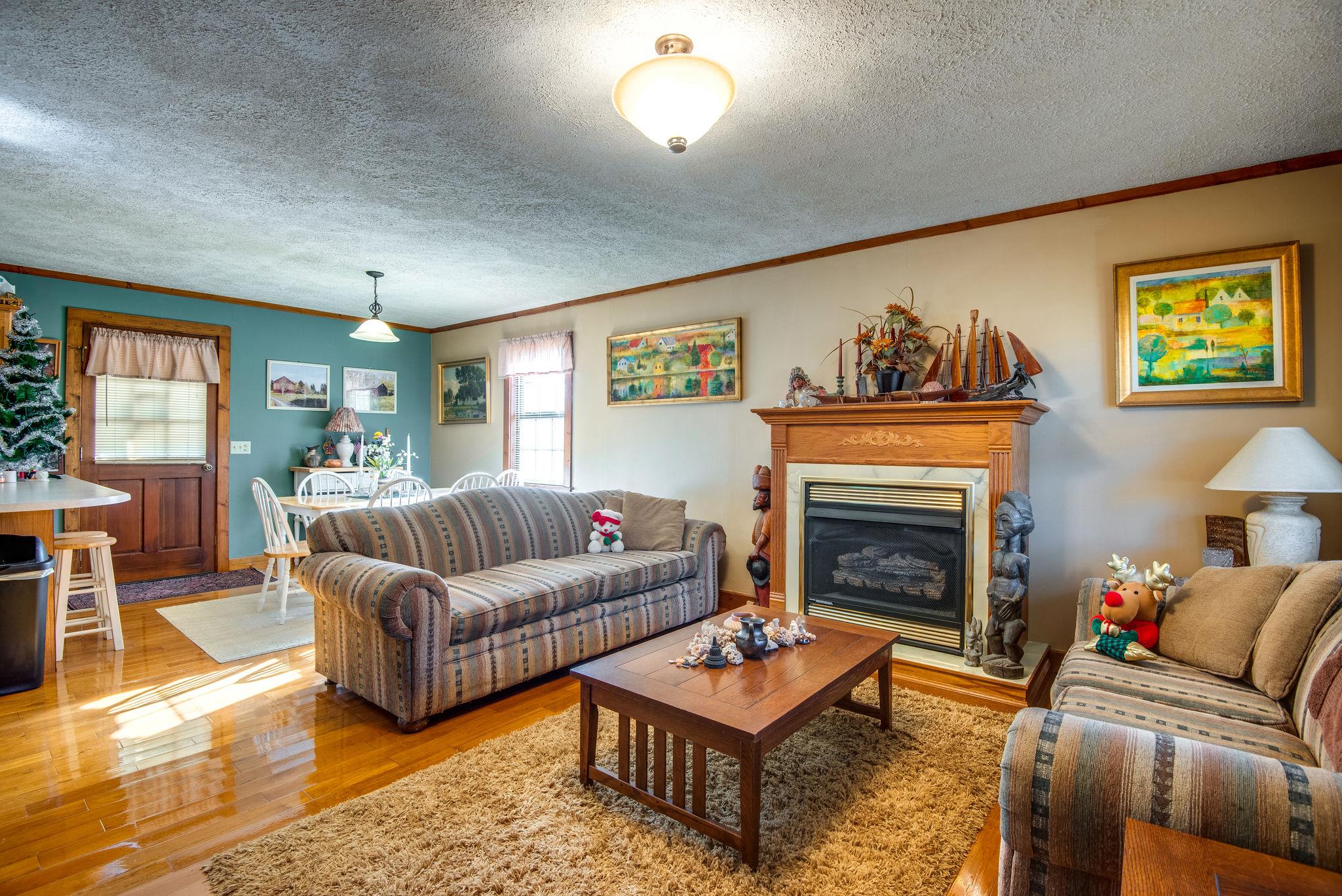 702 Mathis Road Charlotte, TN 37036 - Photo 5 of 22 Cozy interior offers a fireplace, hardwood, and open living area to the dining and kitchen.