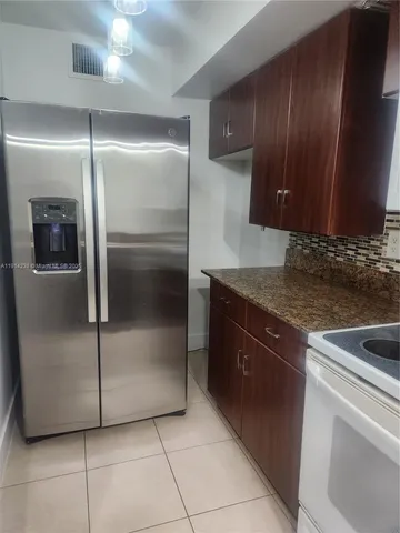 a kitchen with granite countertop a refrigerator and a sink