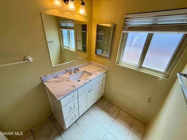 a bathroom with a sink and mirror with bathtub