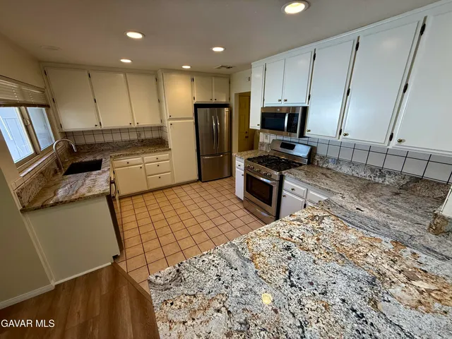 a kitchen with stainless steel appliances granite countertop a sink refrigerator and microwave