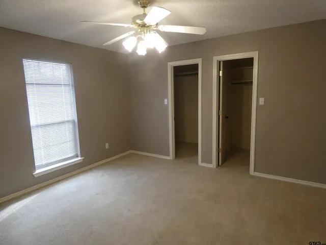 an empty room with windows and fan