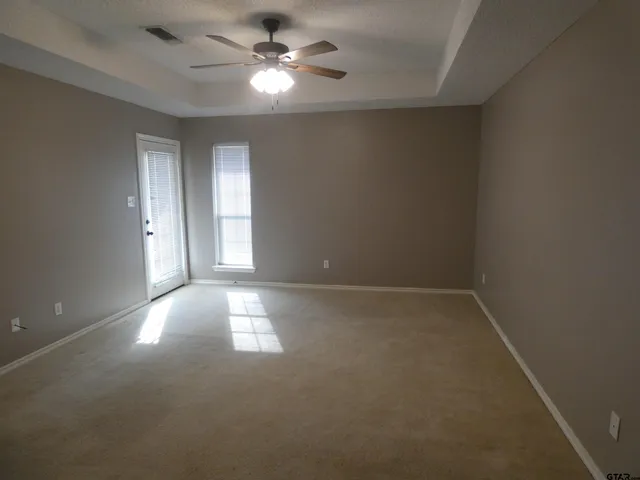 an empty room with a window and a fan