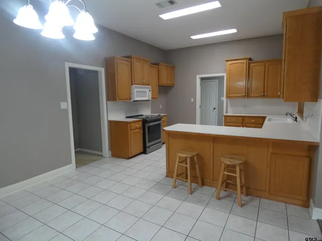 a kitchen with stainless steel appliances granite countertop a stove a sink a refrigerator and a wooden cabinets