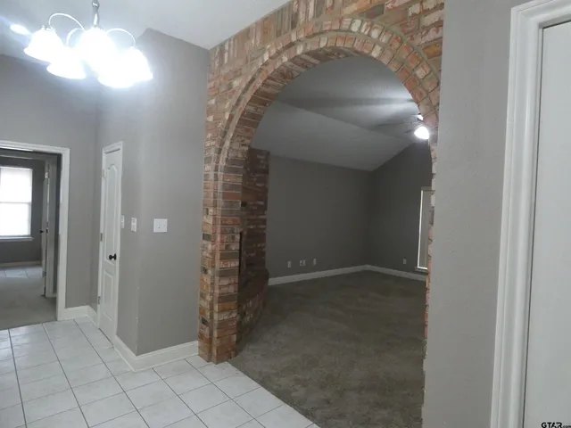 an empty room with a fireplace and chandelier fan