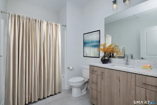 a bathroom with a granite countertop sink toilet and mirror