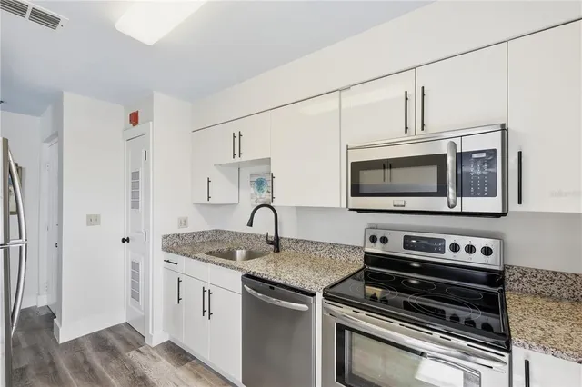 a kitchen with stainless steel appliances granite countertop a stove microwave and refrigerator