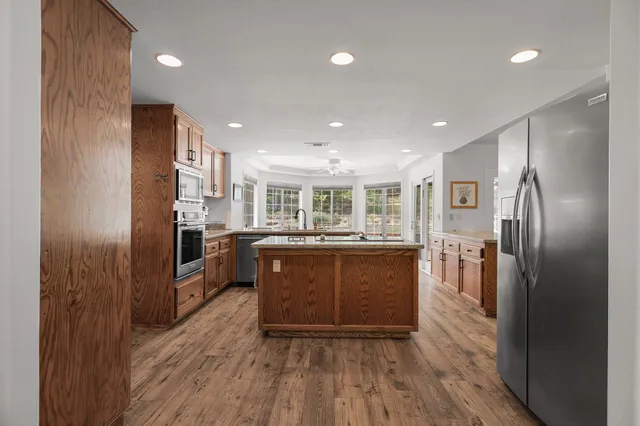 a kitchen with stainless steel appliances granite countertop a refrigerator a sink a stove and oven