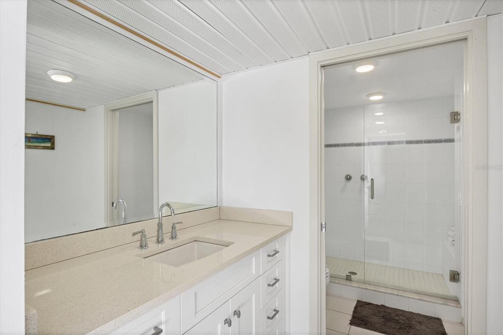 5801 Gulf Of Mexico Drive Longboat Key, FL 34228 - Photo 25 of 52 a bathroom with a shower sink vanity and mirror