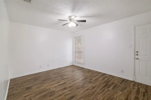 a view of a room with wooden floor and a ceiling fan