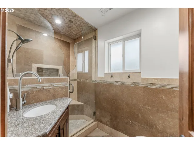 a bathroom with a granite countertop sink a mirror and shower