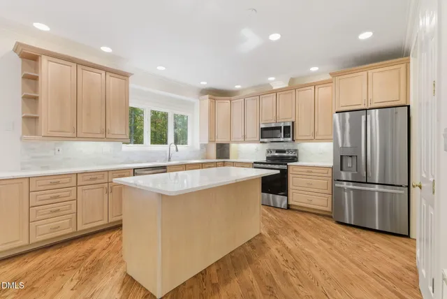 a kitchen with kitchen island granite countertop a refrigerator oven a sink dishwasher and white cabinets with wooden floor