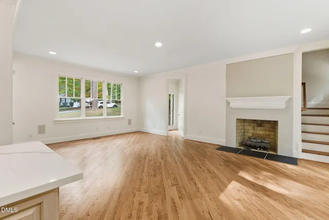 an empty room with windows and fireplace