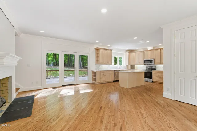 a large white kitchen with wooden floors and a fireplace