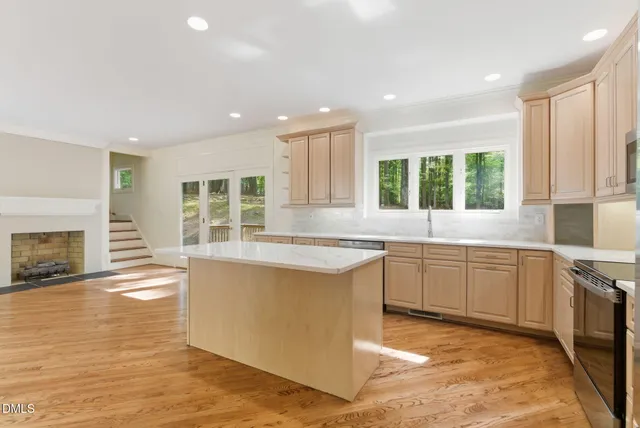 a kitchen with granite countertop a stove a sink a window and dining table