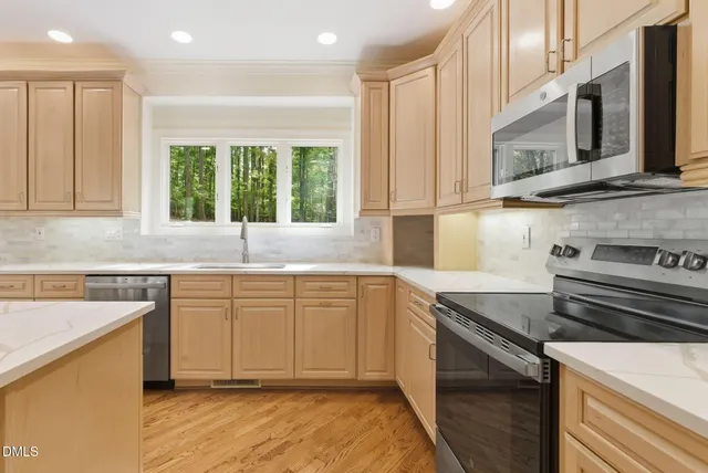 a kitchen with stainless steel appliances white cabinets a sink and a stove