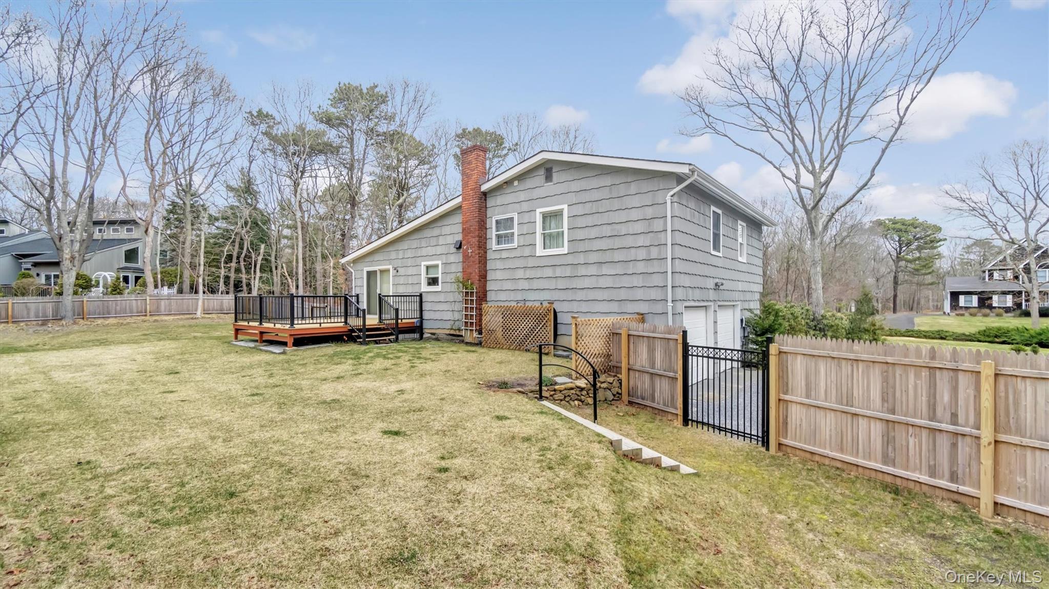 3 Debbie Trail Hampton Bays, NY 11946 - Photo 17 of 29 Back of property with a wooden deck, a fenced backyard, a chimney, and a garage