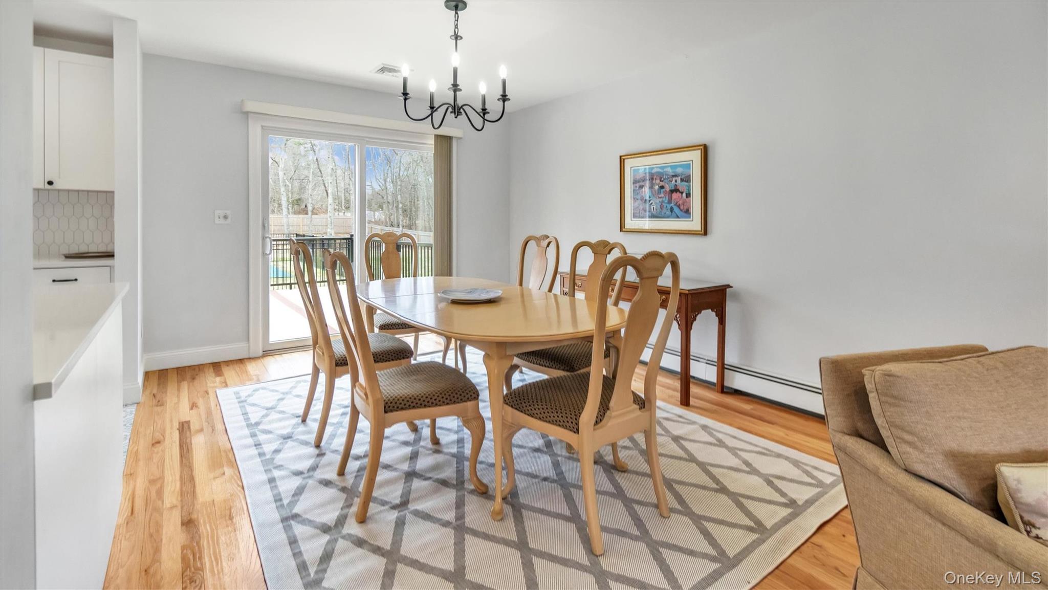 3 Debbie Trail Hampton Bays, NY 11946 - Photo 20 of 29 Dining area with a baseboard radiator, a chandelier, light wood-style flooring, baseboards, and visible vents