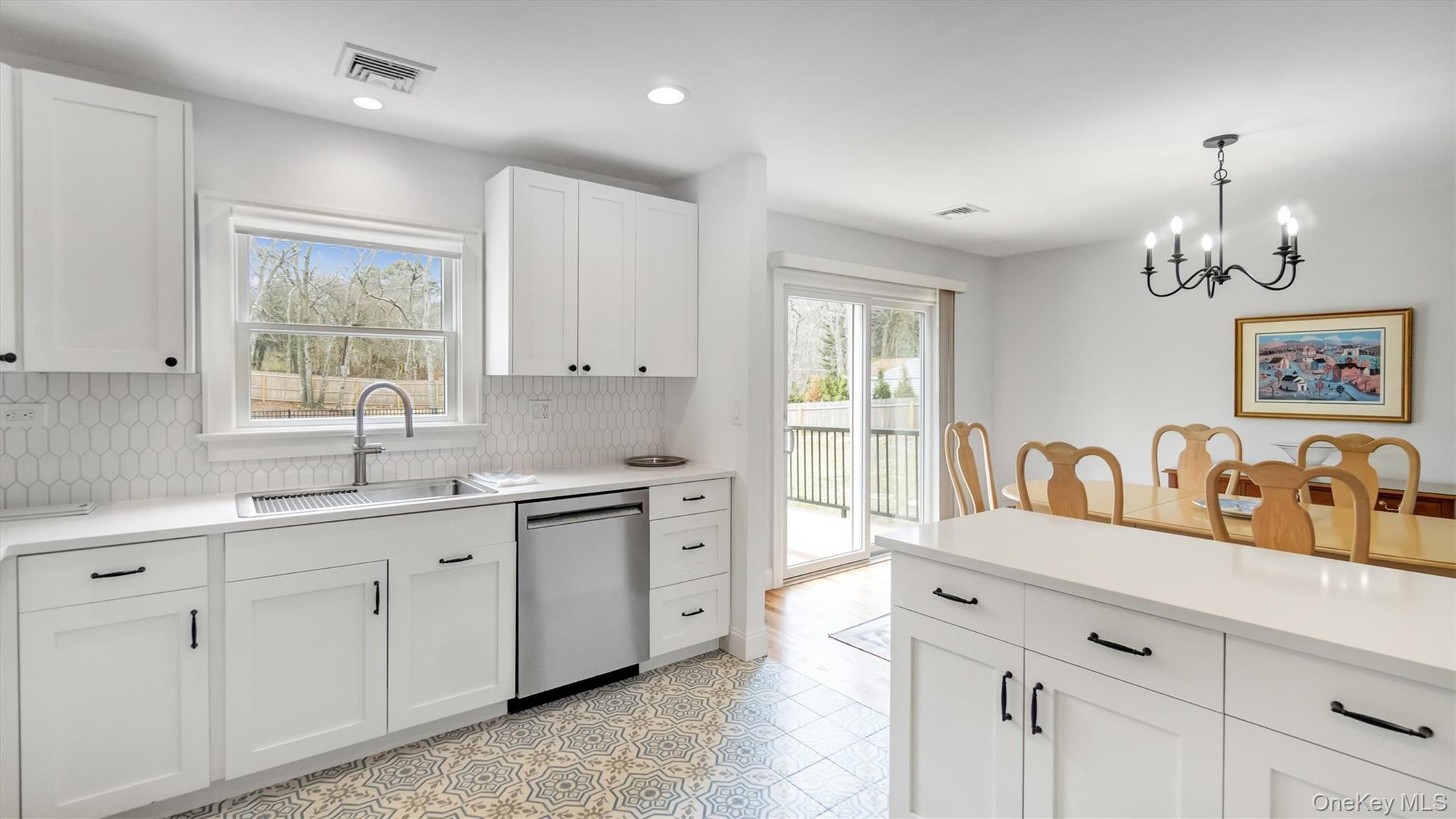 3 Debbie Trail Hampton Bays, NY 11946 - Photo 23 of 29 Kitchen with stainless steel dishwasher, tasteful backsplash, a sink, a chandelier, and white cabinetry