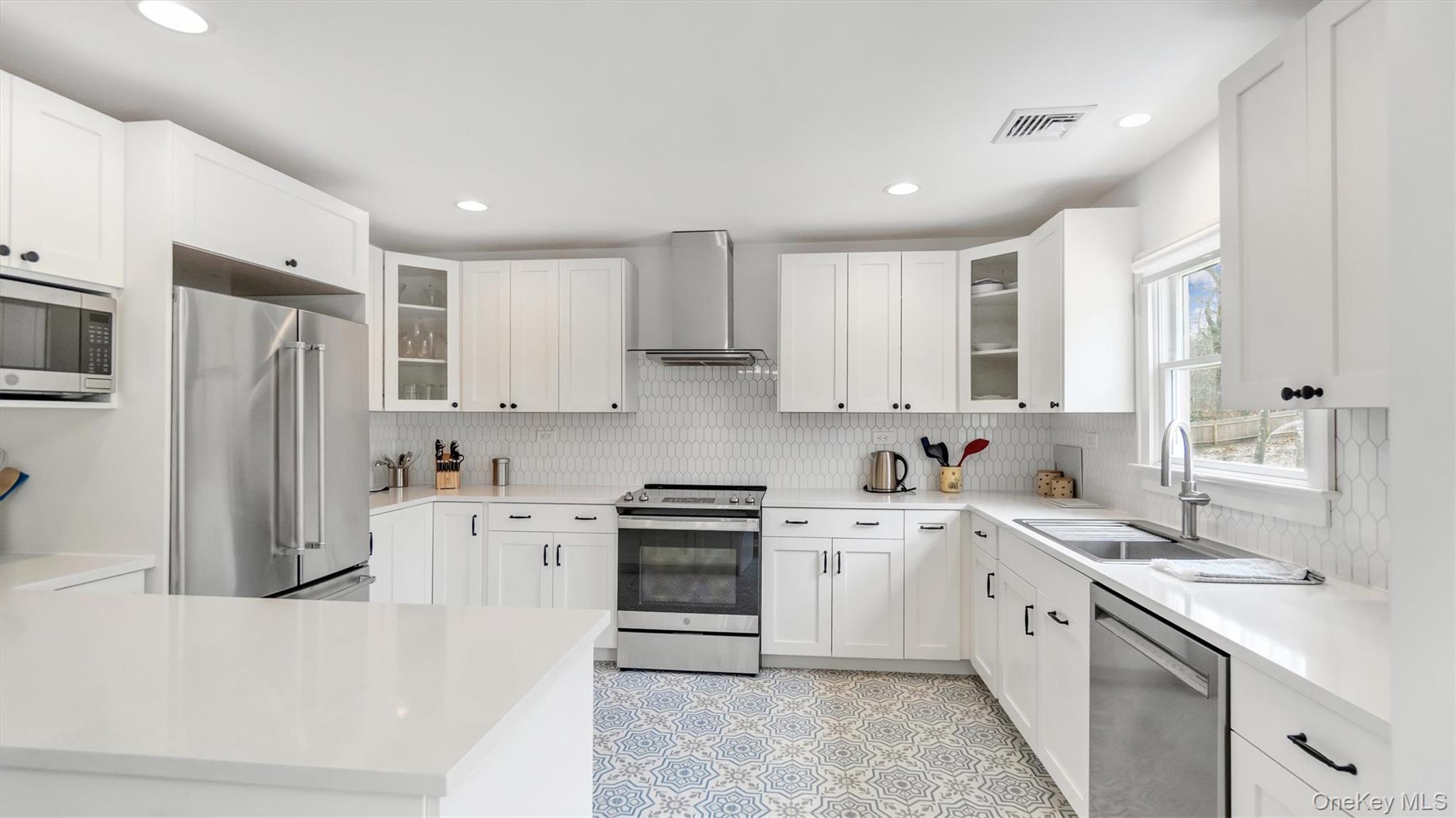 3 Debbie Trail Hampton Bays, NY 11946 - Photo 24 of 29 Kitchen with wall chimney range hood, a sink, stainless steel appliances, backsplash, and visible vents