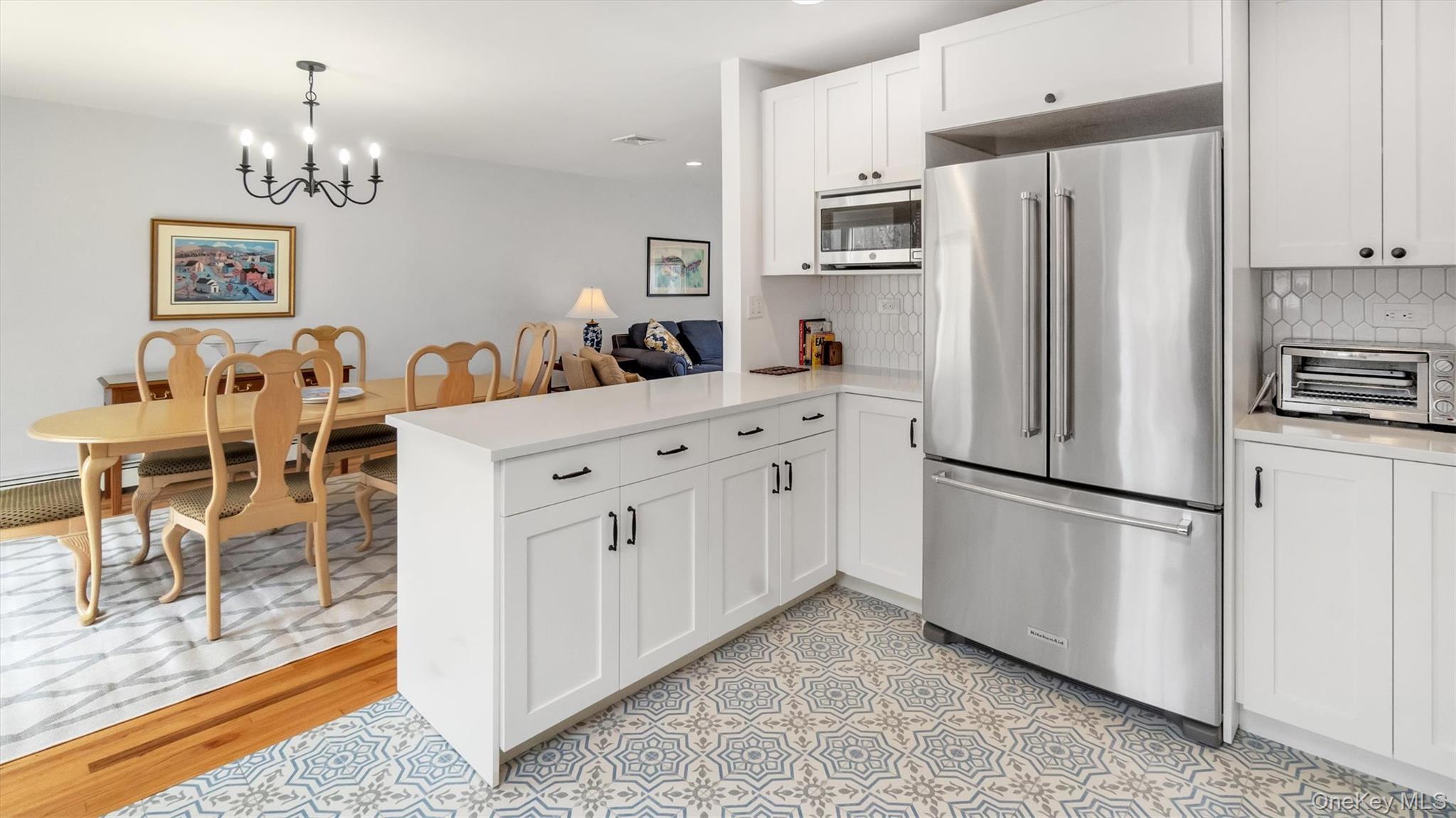 3 Debbie Trail Hampton Bays, NY 11946 - Photo 25 of 29 Kitchen featuring a chandelier, stainless steel appliances, light countertops, backsplash, and a peninsula